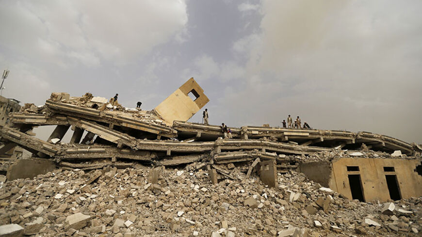 People look through the wreckage of the headquarters of Yemen's Islamist Islah party in the northwestern city of Amran July 14, 2014. According to local media, the five-story building was bombed by Shi'ite Muslim tribesmen known as Houthis during recent fighting against army forces in Amran, and there were no casualties. Yemen's president on Sunday demanded the withdrawal of Shi'ite Muslim tribesmen from the provincial city of Amran captured on July 8, in a stand-off that threatens to intensify turmoil in t