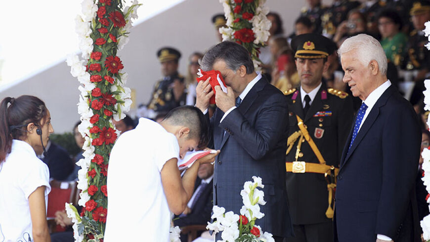Turkish President Abdullah Gul (R) exchanges flags with a Turkish Cypriot youth during a military parade marking 40 years from the invasion of northern Cyprus, in the Cypriot capital Nicosia July 20 2014. Turkish forces landed on the island four decades ago in response to a brief Greek Cypriot coup, partitioning the island since.  REUTERS/Andreas Manolis (CYPRUS - Tags: POLITICS ANNIVERSARY MILITARY) - RTR3ZEDW