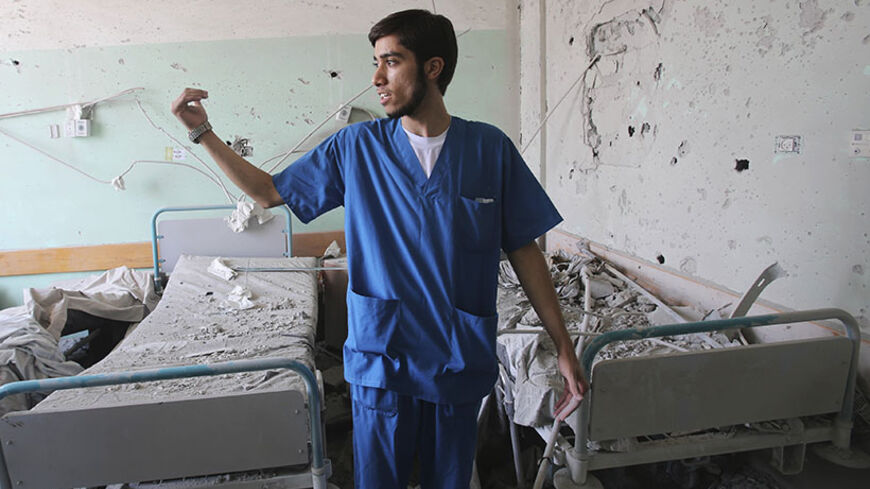 A Palestinian medic gestures at Al-Aqsa hospital, which witnesses said was damaged in an Israeli shelling on Monday, in Deir El-Balah in the central Gaza Strip July 22, 2014. Israel pounded targets across the Gaza Strip on Tuesday, dashing hopes of a pause in the fighting, as the military said one of its soldiers was missing, presumed dead, following clashes with Hamas Islamists. Israel launched its offensive on July 8 to halt missile fire out of Gaza by Hamas, which was angered by a crackdown on its suppor