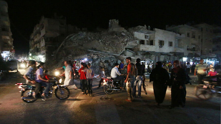 People walk past damaged buildings as they shop on the eve of Eid al-Fitr in Idlib countryside July 27, 2014. The Eid al-Fitr festival marks the end of the Muslim holy fasting month of Ramadan. Picture taken July 27, 2014. REUTERS/Nour Kelze  (SYRIA - Tags: POLITICS CIVIL UNREST CONFLICT RELIGION) - RTR40CM6