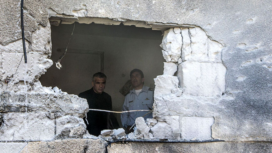 Israeli Finance Minister Yair Lapid (L) inspects the damage inside a house following a rocket attack by militants from the Gaza Strip on the southern Israeli town of Sderot, on July 21, 2014. More than 10 militants from Gaza were shot dead after infiltrating southern Israel, the army's official spokesman said, as the UN Security Council called for an "immediate ceasefire" as Israel pressed on with a blistering assault on Gaza on Monday taking the Palestinian death toll above 500. AFP PHOTO / JACK GUEZ      