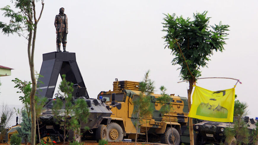 A picture taken on August 19, 2014 in Diyarbakir shows a statue depicting Mahsum Korkmaz , one of the founders of the outlawed Kurdistan Workers Party (PKK), surrounded by Turkish armoured vehicles. One person was killed and two were wounded in the clashes that erupted when a group of protesters gathered at the cemetery to prevent security forces from removing the statue. Mehdi Taskin, 24, died at Dicle University Medical Faculty Hospital after reportedly being shot in the head. AFP PHOTO/ILYAS AKENGIN     