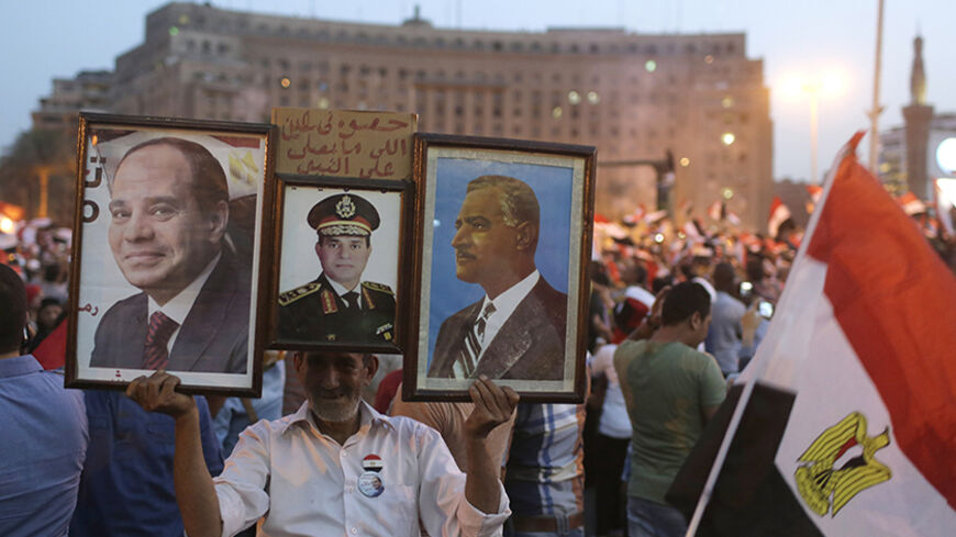 A man carries pictures of Egyptian army chief Abdel Fattah al-Sisi and late president Gamal Abdel-Nasser (R) as Egyptians gather in Tahrir square to celebrate al-Sisi's victory in presidential vote in Cairo, June 3, 2014. Sisi won 96.91 percent in a presidential vote last week, the election commission said on Tuesday, confirming interim results that had given him a landslide victory.REUTERS/Asmaa Waguih (EGYPT - Tags: POLITICS) - RTR3S24G