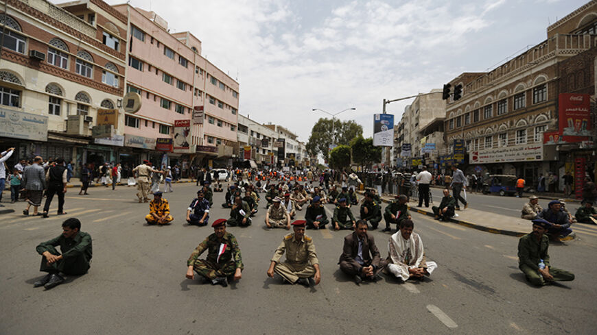 Army and police officers sit on the ground during a protest to denounce fuel prices hikes in Sanaa August 4, 2014. Yemen raised fuel prices last week, oil officials told Reuters, as the impoverished country tries to cut energy subsidies to ease the burden on its budget deficit. REUTERS/Khaled Abdullah (YEMEN - Tags: POLITICS CIVIL UNREST ENERGY MILITARY) - RTR415WW