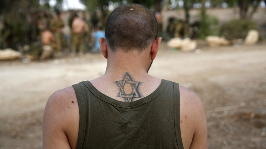 An Israeli soldier from the Nahal Brigade with a Star of David tattoo is seen after returning to Israel from Gaza August 5, 2014. Israel pulled its ground forces out of the Gaza Strip on Tuesday and started a 72-hour ceasefire with Hamas mediated by Egypt as a first step towards negotiations on a more enduring end to the month-old war. REUTERS/Baz Ratner (ISRAEL - Tags: POLITICS CONFLICT CIVIL UNREST MILITARY) - RTR41AQ9