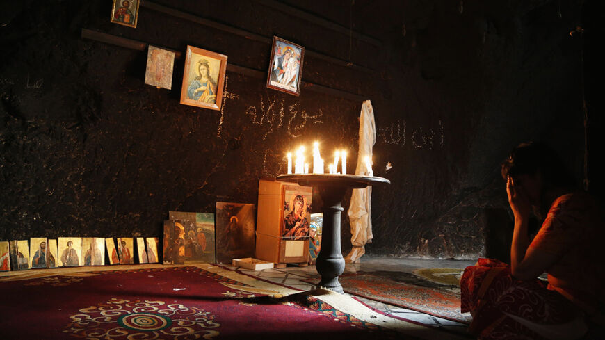 A woman prays inside a damaged church in Maaloula August 21, 2014. Residents of Maaloula, a Christian town in Syria, call on other Christian groups and minorities to stand up to the radicalism that is sweeping across Syria and Iraq. The town was regained by Syrian Army forces in April from Islamic militants, and several months later life is slowly returning to the town. REUTERS/Omar Sanadiki (SYRIA - Tags: POLITICS SOCIETY RELIGION) - RTR43A30
