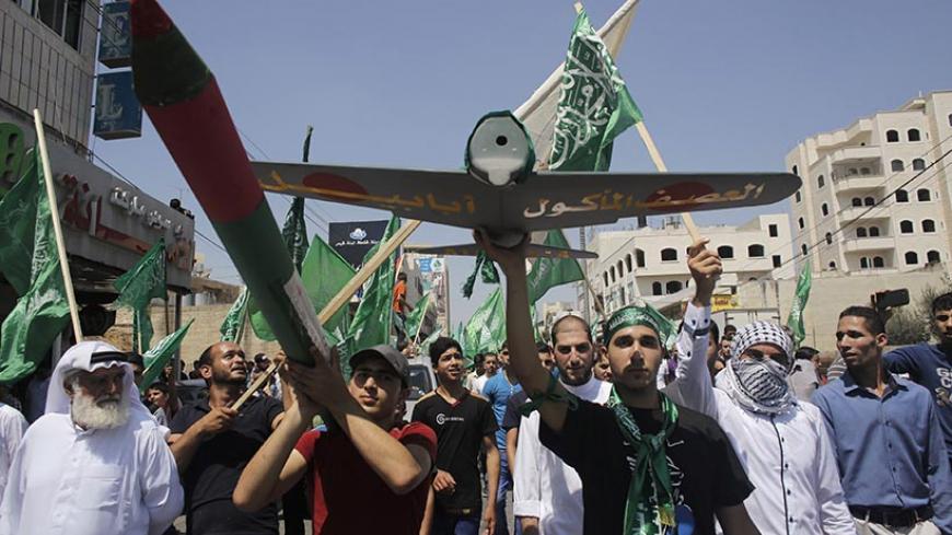 Palestinians hold a mock rocket and a model of a Hamas-made drone during a rally celebrating what they said was a victory by Palestinians in Gaza over Israel, following a ceasefire, in the West Bank city of Hebron August 29, 2014. An open-ended ceasefire, mediated by Egypt, took effect on Tuesday evening. It called for an indefinite halt to hostilities, the immediate opening of Gaza's blockaded crossings with Israel and Egypt, and a widening of the territory's fishing zone in the Mediterranean. Israel launc