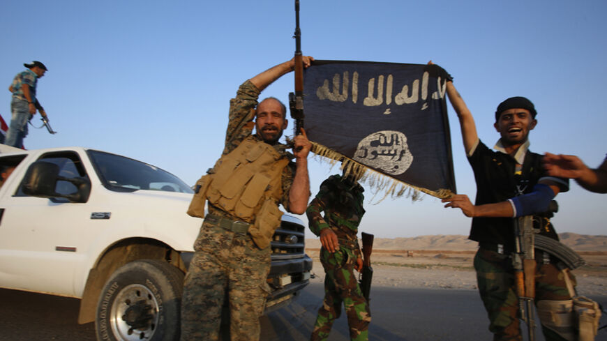 Iraqi Shiite militia fighters hold the Islamic State flag as they celebrate after breaking the siege of Amerli by Islamic State militants, September 1, 2014.   Picture taken on September 1, 2014.  REUTERS/Youssef Boudlal (IRAQ - Tags: CIVIL UNREST POLITICS MILITARY TPX IMAGES OF THE DAY) - RTR44N6G