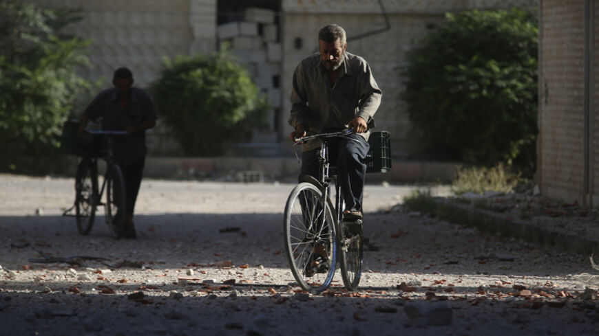 A man rides his bicycle along a street filled with debris in the Duma neighbourhood of Damascus September 10, 2014. REUTERS/Bassam Khabieh (SYRIA - Tags: POLITICS CIVIL UNREST CONFLICT) - RTR45MM4