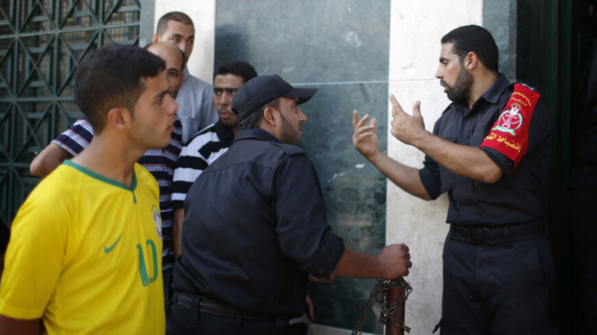 Police officers take charge as Palestinian Hamas-hired employees wait to receive partial payments outside a bank in Gaza City September 11, 2014. Tensions between Fatah and Hamas, the two main Palestinian parties, are close to breaking point over the non-payment of salaries to Gaza's public sector workers, raising the risk of a return to conflict in the territory, officials say. As a stop-gap measure, the Hamas-controlled Finance Ministry in Gaza announced on Wednesday it would make partial payments, betwee