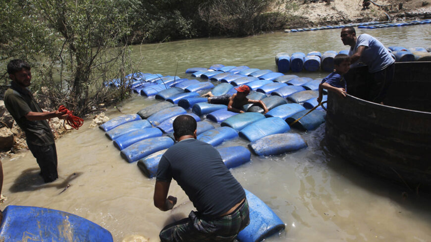 A group of men smuggle diesel fuel from Syria to Turkey hoping to sell it at a higher price, across the Al-Assi River in Darkush town, Idlib countryside May 26, 2013. REUTERS/Muzaffar Salman (SYRIA - Tags: CONFLICT TPX IMAGES OF THE DAY) - RTX1026I