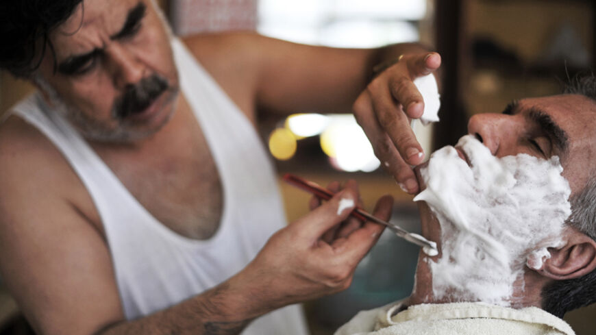 TO GO WITH STORY BY PHILIPPE ALFROY
A Turkish barber Mehmet Haskan shaves a client at his salon at Tarlabasi on July 19, 2013 in Istanbul.  AFP PHOTO/OZAN KOSE        (Photo credit should read OZAN KOSE/AFP/Getty Images)