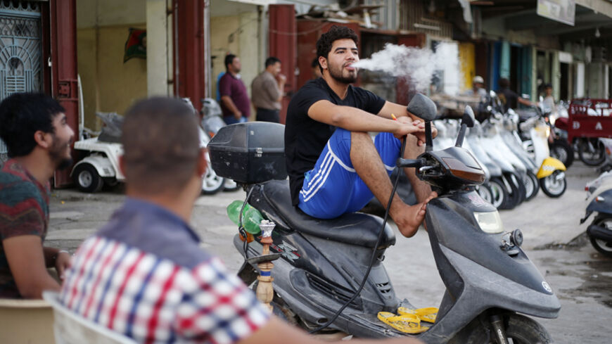 An Iraqi Shi'ite youth smokes a water pipe while sitting on a motorcycle in Sadr City in Baghdad April 27, 2014. Iraq is now gripped by its worst violence since the heights of its 2005-2008 sectarian war, and Sunni Islamist insurgents who target Shi'ites have been regaining ground in the country over the past year. But despite the instability, daily life continues in poor Shi'ite neighbourhoods of Baghdad such as Al-Fdhiliya and Sadr City - a sprawling slum marred by poor infrastructure and overcrowding. Pi