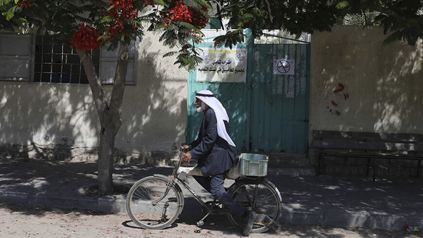 A Palestinian man rides his bicycle past the office of the Ministry of Education in Khan Younis in the southern Gaza Strip June 26, 2014. Some 40,000 public servants hired by Hamas went on strike in Gaza on Thursday in a pay dispute that could test the resilience of the new Palestinian government, formed just weeks ago under the Islamist group's unity pact with President Mahmoud Abbas. All government offices in the Hamas-controlled Gaza Strip were closed as a result of the one-day strike, but hospital emerg