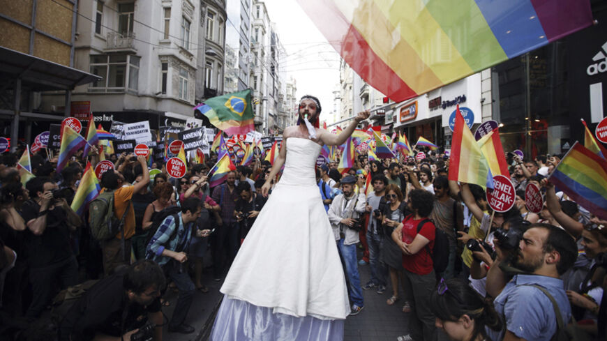 A participant wears a bridal dress as he waves the rainbow flag during a gay pride parade in central Istanbul June 29, 2014. REUTERS/Osman Orsal (TURKEY - Tags: CIVIL UNREST SOCIETY POLITICS TPX IMAGES OF THE DAY) - RTR3WBAI