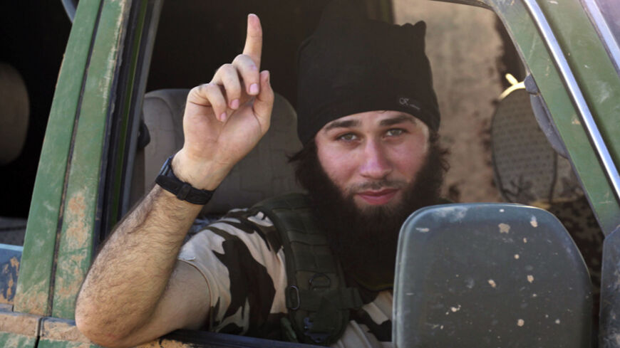 An Islamic State fighter gestures from a vehicle in the countryside of the Syrian Kurdish town of Kobani, after the Islamic State fighters took control of the area October 7, 2014. U.S.-led air strikes on Wednesday pushed Islamic State fighters back to the edges of the Syrian Kurdish border town of Kobani, which they had appeared set to seize after a three-week assault, local officials said. Picture taken October 7, 2014. REUTERS/Stringer (SYRIA - Tags: POLITICS CIVIL UNREST CONFLICT) - RTR49CW1