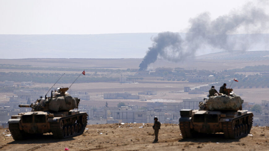 Smoke rises from the Syrian town of Kobani, Turkish army tanks take position on the Turkish side of the border, as seen from near the Mursitpinar border crossing on the Turkish-Syrian border in Sanliurfa province October 8, 2014. U.S.-led air strikes on Wednesday pushed Islamic State fighters back to the edges of the Syrian Kurdish border town of Kobani, which they had appeared set to seize after a three-week assault, local officials said. REUTERS/Umit Bektas (TURKEY - Tags: MILITARY CONFLICT POLITICS TPX I