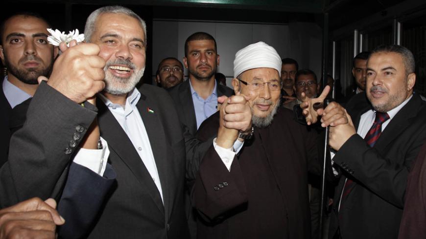Hamas Prime Minister Ismail Haniyeh (L) holds the hand of Egyptian Cleric and chairman of the International Union of Muslim Scholars Sheikh Yusuf al-Qaradawi (R) upon al-Qaradawi's arrival at Rafah Crossing in the southern Gaza Strip May 8, 2013. Al-Qaradawi arrived on Wednesday for a three-day visit to Gaza Strip with a delegation of Muslim scholars. REUTERS/Ibraheem Abu Mustafa (GAZA - Tags: POLITICS RELIGION) - RTXZFCT