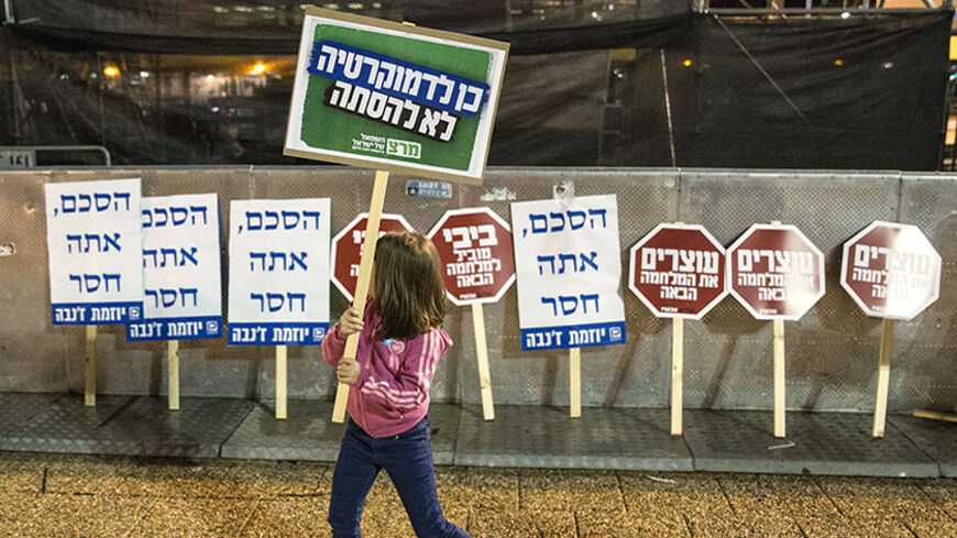 A young Israeli demonstrator holds up a placard that reads "Democracy no diversion"  during rally to mark the 19th anniversary of the assassination of former Israeli Prime Minister Yitzhak Rabin at the Tel Aviv plaza where he was shot  in the Mediterranean coastal city of Tel Aviv on November 1, 2014. Rabin was shot dead on November 4, 1995 just two years after the signing of the Oslo peace accords, for which he and former President Shimon Peres were awarded the Nobel Peace Prize along with veteran Palestin