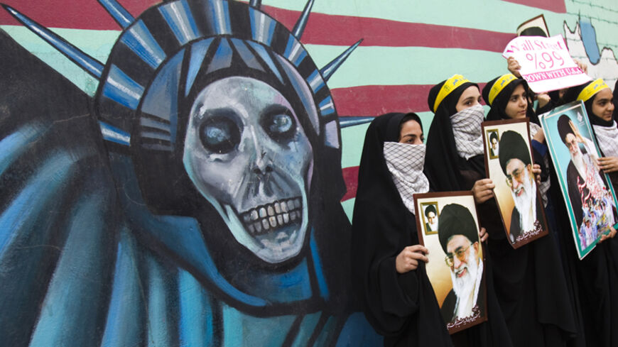 EDITORS' NOTE: Reuters and other foreign media are subject to Iranian restrictions on their ability to film or take pictures in Tehran.

Iranian students holding pictures of Iran's Supreme Leader Ayatollah Ali Khamenei stand in front of an anti U.S. mural, painted on the wall of the former U.S. Embassy in Tehran November 4, 2011. REUTERS/Raheb Homavandi  (IRAN - Tags: POLITICS) - RTR2TLUF