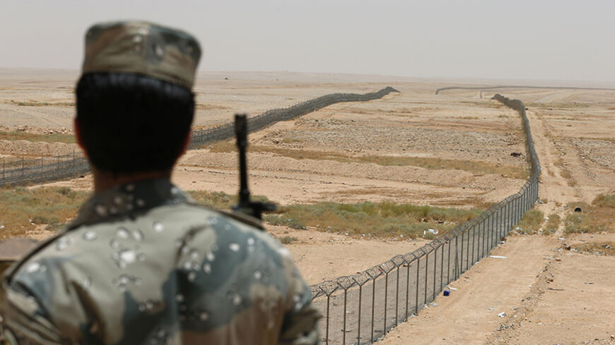 A member of the Saudi border guards force stands guard next to a fence on Saudi Arabia's northern borderline with Iraq July 14, 2014. Three mortar bombs landed inside Saudi Arabia last week close to its northern border with Iraq, where Islamist militants have grabbed land in a lightning advance, officials said. REUTERS/Faisal Al Nasser (SAUDI ARABIA - Tags: POLITICS MILITARY CIVIL UNREST TPX IMAGES OF THE DAY) - RTR3YMVB