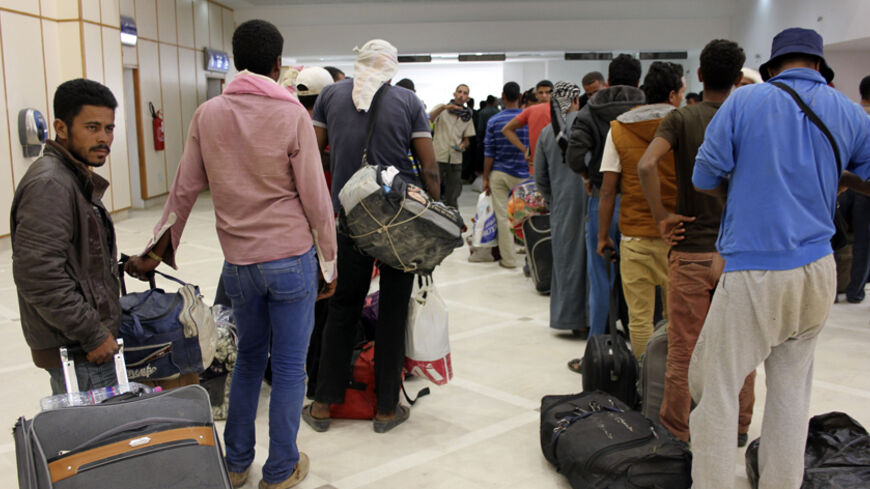 Egyptian men wait to board their plane to return home, at the Gabes Matmata airport, south of Tunisia August 6, 2014. According to media reports, Egyptians fleeing the violence in Tripoli were picked up at the Libya-Tunisia border, and will be evacuated back to Egypt. Tunisia said on July 30 it might close its frontiers with Libya if the security situation continues to worsen. A steady stream of foreigners have been evacuated from Libya since the fighting began last month. REUTERS/Stringer (TUNISIA - Tags: 