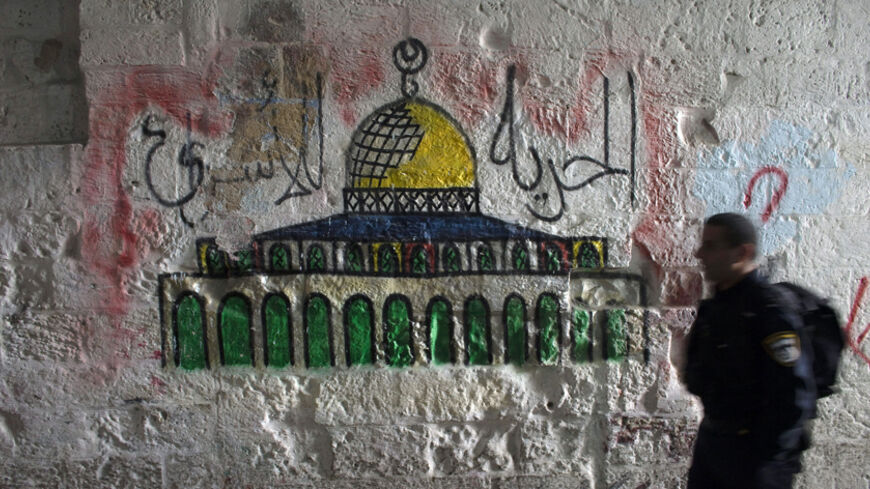 An Israeli police officer walks past a mural of the Dome of the Rock near the entrance to the compound known to Muslims as Noble Sanctuary and to Jews as Temple Mount, in Jerusalem's Old City October 19, 2014. Clashes have flared repeatedly in the past few weeks as increasing numbers of Jews have visited the sacred area during the Jewish holidays, angering Palestinians who see this as part of an Israeli agenda to alter a long-preserved status quo. The words on the wall read, "Freedom to prisoners". REUTERS/