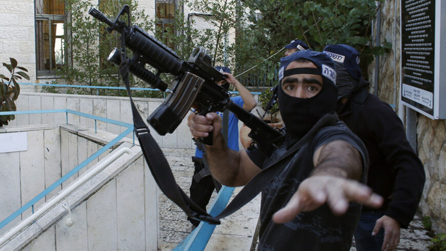 An Israeli police officer gestures as he holds a weapon near the scene of an attack at a Jerusalem synagogue November 18, 2014. Two suspected Palestinian men armed with axes and knives killed four people in a Jerusalem synagogue on Tuesday before being shot dead by police, Israeli police and emergency services said, the deadliest such attack in the city in years. REUTERS/Ronen Zvulun (JERUSALEM - Tags: CIVIL UNREST POLITICS TPX IMAGES OF THE DAY) - RTR4EK6L