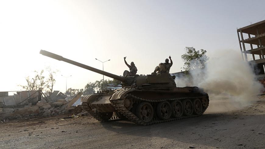 Fighters from the Benghazi Shura Council, which includes former rebels and militants from al Qaeda-linked Ansar al-Sharia, gesture on top of a tank next to the camp of the special forces in Benghazi July 30, 2014. On Wednesday, the eastern city of Benghazi was quieter after Islamist fighters and allied militia forces overran a special forces army base in the city in a major blow to a military campaign against Islamist militants there. The self-declared Benghazi Shura Council forces took over the base on Tue