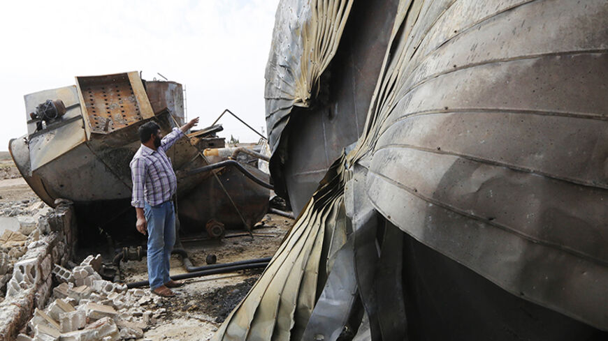 A man points at damage at an oil refinery and a gas station that were targeted by what activists said were U.S.-led air strikes, in the town of Tel Abyad of Raqqa governorate, near the border with Turkey October 2, 2014. Air strikes believed to have been carried out by U.S.-led forces hit three makeshift oil refineries in Syria's Raqqa province early on Sunday as part of an assault to weaken Islamic State (IS) militants, a human rights group said. The United States has been carrying out strikes in Iraq agai