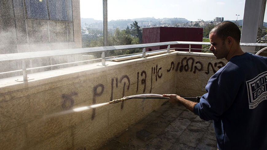 A worker sprays water as he cleans a wall scrawled with graffiti in an Arab-Jewish school in Jerusalem November 30, 2014. Suspected Jewish extremists set fire to a classroom in the school in Jerusalem, police said on Sunday, targeting a symbol of co-existence in a city on edge over a recent surge in violence.
  REUTERS/Ronen Zvulun (JERUSALEM - Tags: POLITICS CIVIL UNREST EDUCATION) - RTR4G4AL