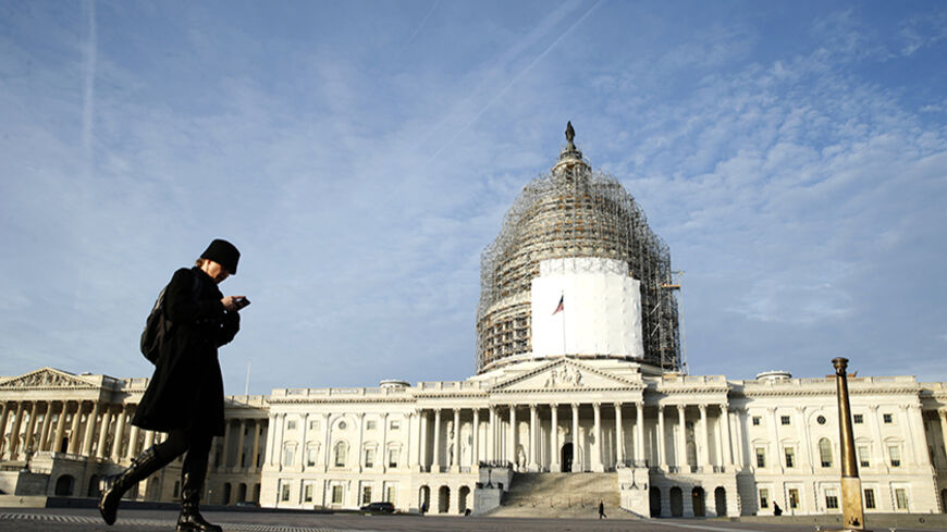 A woman checks her smartphone as she walks past the U.S. Capitol in Washington December 4,  2014.  U.S. President Barack Obama voiced optimism on Wednesday that a government shutdown can be avoided in coming weeks, pointing to comments from Republican leaders of Congress who oppose a budget showdown.  
REUTERS/Kevin Lamarque  (UNITED STATES - Tags: POLITICS BUSINESS SOCIETY) - RTR4GPPO