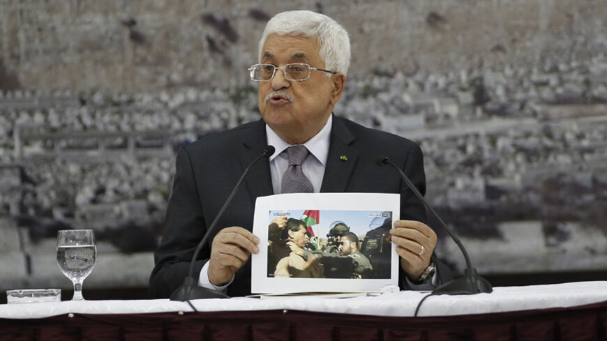 Palestinian President Mahmoud Abbas shows a picture of Palestinian minister Ziad Abu Ein as he is grabbed by an Israeli border policeman, during a meeting with the Palestinian leadership in the West Bank city of Ramallah December 10, 2014. Abu Ein died on Wednesday shortly after the Israeli border policeman shoved and grabbed him by the throat during the protest in the West Bank, an incident Abbas described as barbaric. Abu Ein, 55, a minister without portfolio, was among scores of Palestinian and foreign a