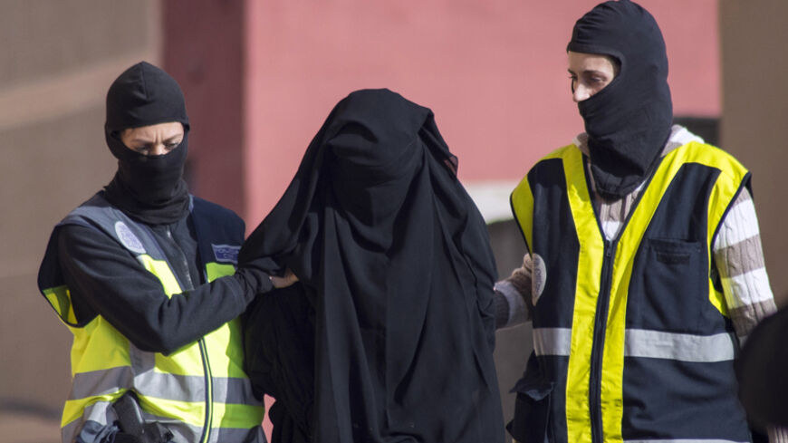 Masked Spanish police officers lead a detained woman in Melilla, December 16, 2014. Spanish and Moroccan police have arrested seven people in a ongoing joint swoop on suspected efforts to recruit women to go to Syria and Iraq to support Islamic State insurgents, the Spanish Interior Ministry said on Tuesday. REUTERS/Jesus Blasco de Avellaneda  (SPAIN - Tags: CRIME LAW CIVIL UNREST TPX IMAGES OF THE DAY) - RTR4I81E
