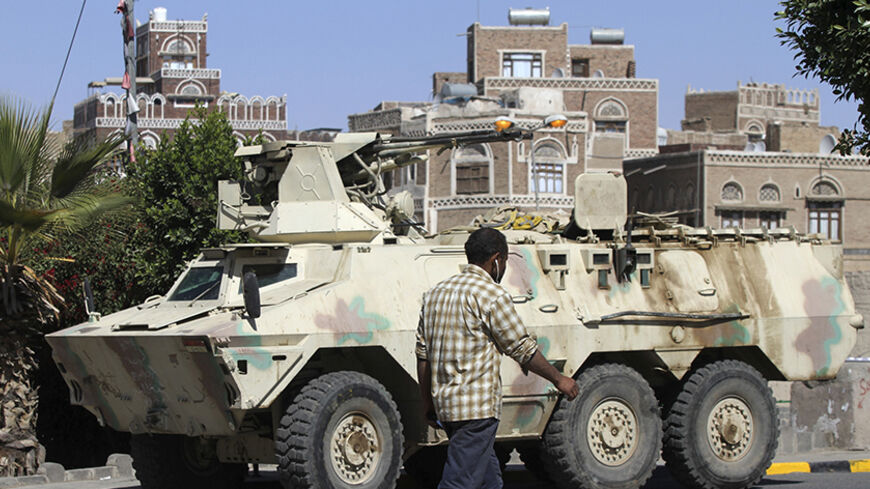 A man walks past an armoured vehicle belonging to Shi'ite Houthi fighters, which was seized from the army recently, near the Defence Ministry compound in Sanaa December 17, 2014.  REUTERS/Mohamed al-Sayaghi (YEMEN - Tags: MILITARY CIVIL UNREST) - RTR4IFCA