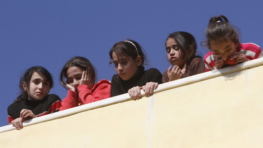 Palestinian girls watch as mourners carry the body of 17-year-old Palestinian Imam Dwikat, who was shot dead by Israeli troops, during his funeral in the West Bank village of Beita near Nablus December 30, 2014. Israeli soldiers shot and killed Dwikat who had been hurling rocks at cars on a highway in the occupied West Bank on Monday, a military spokeswoman said. She said troops shouted at a group of Palestinians throwing stones on a main road near Palestinian villages and Jewish settlements to halt and the