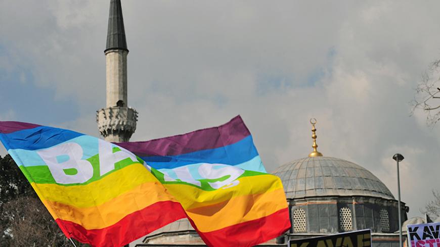 Turkish gay rights group (LAMBDA) activists wave peace flags infront of a mosque in Istanbul on March 16, 2010 during a demonstration against Family Affairs Minister Aliye Selma Kavaf. Some 60 activists denounced Kavaf and called for her resignation, as they accuse the Family Affairs Minister of insult, incitement to crime and incitement to enmity and hate -- crimes which are punishable by up to two, five and three years in jail respectively.  Kavaf, who is also women's minister in the Islamist-rooted gover