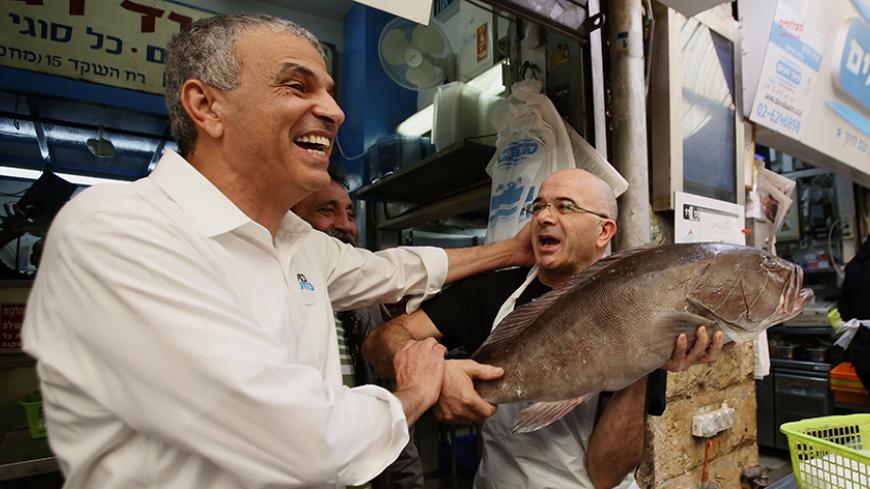 Israeli politician and popular former Likud minister Moshe Kahlon (L) shares a laugh with a fishmonger as he visits the Jerusalem outdoors Mahne Yehuda market on January 21, 2015 during his campaign for the upcoming general election. Kahlon, who in November 2014 announced a comeback, is at the head of a new centre-right party called "Kulanu" (All Of Us). AFP PHOTO / GALI TIBBON        (Photo credit should read GALI TIBBON/AFP/Getty Images)