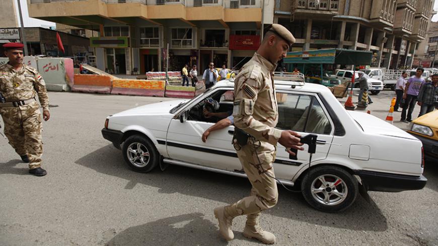 An Iraqi soldier scans a car with a bomb detector a checkpoint at Shurja market in central Baghdad, April 28, 2012.   REUTERS/Thaier al-Sudani (IRAQ - Tags : - Tags: CONFLICT MILITARY) - RTR31CIN