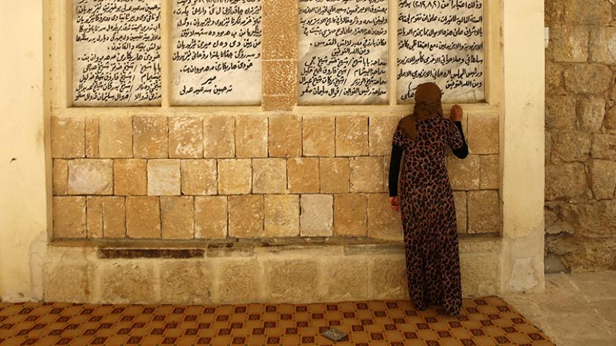 A displaced woman from the minority Yazidi sect, who fled violence in the Iraqi town of Sinjar, worships at their main holy temple in Lalish in Shikhan September 20, 2014. Followers of an ancient religion derived from Zoroastrianism, the Yazidi fled their homeland in the Sinjar mountains as Islamic State militants, who see them as devil worshippers, seized towns and carried out mass killings in August. REUTERS/Ahmed Jadallah (IRAQ - Tags: CIVIL UNREST CONFLICT RELIGION) - RTR471OX