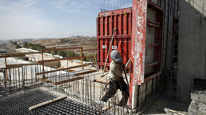 A labourer works on an apartment building under construction in a Jewish settlement known to Israelis as Har Homa and to Palestinians as Jabal Abu Ghneim in an area of the West Bank that Israel captured in a 1967 war and annexed to the city of Jerusalem, October 28, 2014. Israeli Prime Minister Benjamin Netanyahu will expedite planning for some 1,000 settler homes in East Jerusalem, a government official said on Monday, in a bid to placate a restive coalition ally without further aggravating a dispute with 