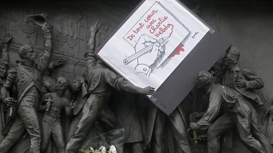 A placard with a press cartoon by cartoonist Plantu is placed amongst a frieze on the Republic statue at the Place de la Republique in Paris January 8, 2015 the day after a shooting at the Paris offices of weekly satirical newspaper Charlie Hebdo. French police extended a manhunt on Thursday for two brothers suspected of killing 12 people at a satirical magazine in Paris in a presumed Islamist militant strike that national leaders and allied states described as an assault on democracy. France began a day of