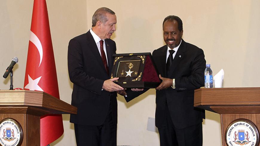 Turkey's President Tayyip Erdogan (L) receives a gift from Somalia's President Hassan Sheikh Mohamud (R) after addressing a joint news conference in Somalia's capital Mogadishu January 25, 2015. Turkish President Tayyip Erdogan travelled to the Somali capital Mogadishu under heavy security on Sunday, making his second visit in four years to promise further investment in the country as it struggles to rebuild after two decades of conflict. REUTERS/Feisal Omar (SOMALIA - Tags: POLITICS) - RTR4MTPA