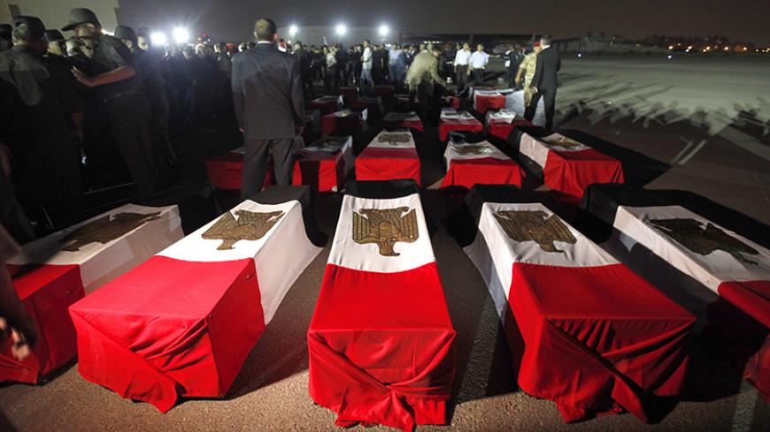 The caskets of 25 policemen killed early Monday morning near the north Sinai town of Rafah lay on the ground after arriving at Almaza military airport in Cairo August 19, 2013. The 25 Egyptian policemen were killed and three others wounded in an ambush by Islamist militants, medical and security sources said. Attacks by Islamist militants in the lawless north Sinai region have intensified since the army overthrew Islamist President Mohamed Mursi on July 3. REUTERS/Mohamed Abd El Ghany (EGYPT - Tags: POLITIC
