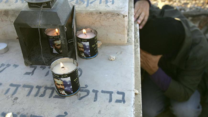 JERUSALEM, :  Candles burn with the image of  the late Brooklyn born Rabbi Meir Kahane as a follower prays at his grave at the Givat Shaul cemetery on the outskirts of Jerusalem 09 November 2006, to mark the 16th anniversary of his assassination by an Arab gunman in Manhattan. The anti-Arab Jewish militant movement founded by Kahane has in the past claimed responsibility for dozens of shootings of Palestinians in the West Bank, including the notorious 1994 massacre of 29 worshippers at a Hebron Mosque. AFP 
