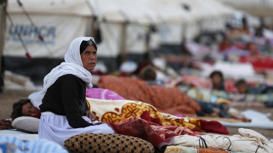 A woman looks on as she sits amongst displaced people from the minority Yazidi sect, who fled violence in the Iraqi town of Sinjar, who are sleeping on the ground at Bajed Kadal refugee camp, southwest of Dohuk province August 23, 2014. REUTERS/Youssef Boudlal (IRAQ - Tags: CIVIL UNREST POLITICS CONFLICT) - RTR43FCQ