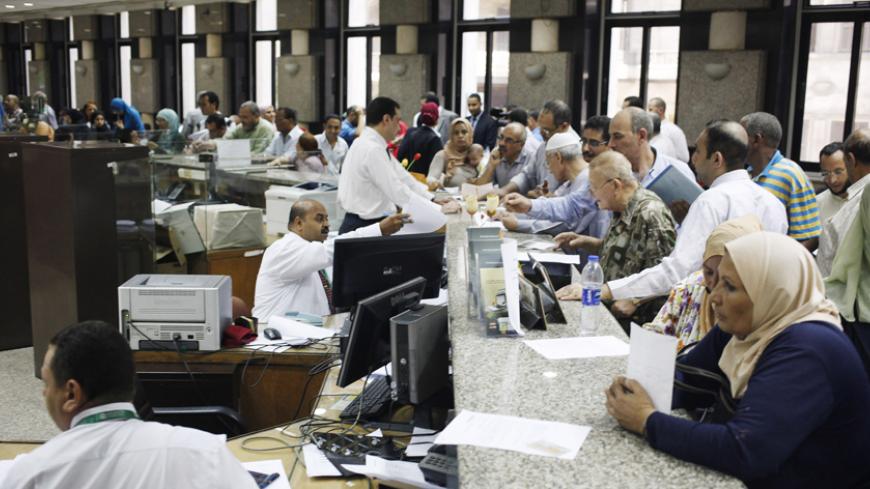 People buy Suez Canal investment certificates at a bank in Cairo September 4, 2014. Egypt issued government certificates to finance the Suez Canal project on Monday, state media said, as the country aims to expand trade along what is the fastest shipping route between Europe and Asia. The five-year investment certificates have a 12 percent interest rate and pay quarterly dividends and will come in 10, 100 and 1,000 Egyptian pound ($1.40-$140) denominations, MENA said. REUTERS/Asmaa Waguih (EGYPT - Tags: BUS
