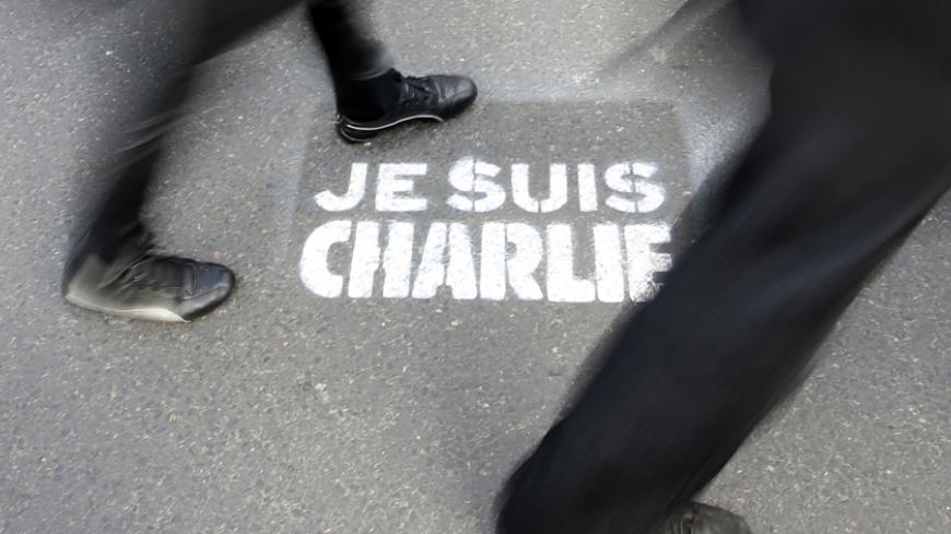 People walk past a grafitti tag reading "I am Charlie" as they take part in a solidarity march (Marche Republicaine) in the streets of Paris January 11, 2015. French citizens will be joined by dozens of foreign leaders, among them Arab and Muslim representatives, in a march on Sunday in an unprecedented tribute to this week's victims following the shootings by gunmen at the offices of the satirical weekly newspaper Charlie Hebdo, the killing of a police woman in Montrouge, and the hostage taking at a kosher
