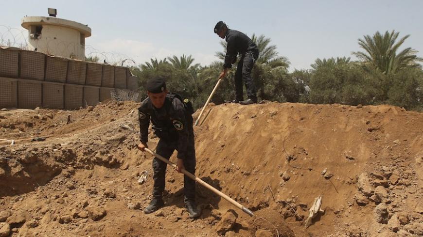 Iraqi policemen dig trenches at checkpoint in the Iraqi town of Taji, at the entrance of Baghdad, on June 13, 2014, as security forces are bolstering defenses in the capital. Jihadist Islamic State of Iraq and the Levant (ISIL) militants pushed towards the capital and US President Barack Obama said he was exploring all options to save Iraq's security forces from collapse. AFP PHOTO / AHMAD AL-RUBAYE        (Photo credit should read AHMAD AL-RUBAYE/AFP/Getty Images)