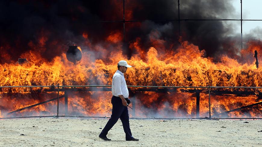 An Iranian employee of the anti-drug police walk past 50 tons of drugs seized in recent months burning in eastern Tehran on June 26, 2014 to mark the International Day Against Drug Abuse and Illicit Trafficking. The Iranian security forces seized some 575 tons of drugs between March 2013 and March 2014, the Iranian Interior Minister Abdolreza Rahmani Fazli said. AFP PHOTO/ATTA KENARE        (Photo credit should read ATTA KENARE/AFP/Getty Images)